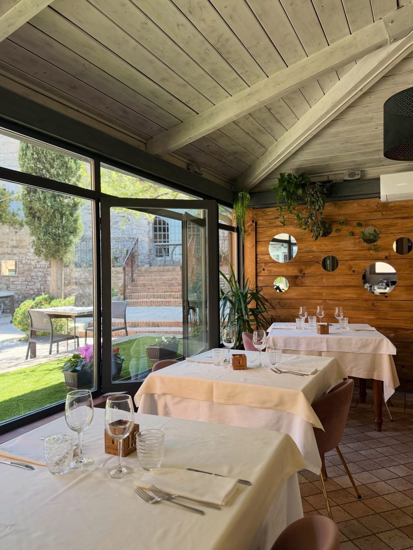 La veranda con le vetrate sul giardino e la parete di legno con gli specchi tondi